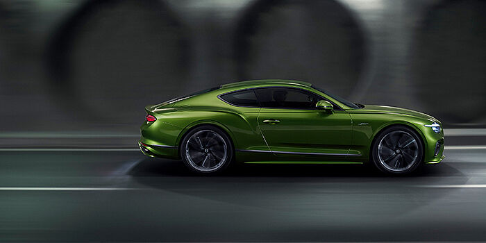  Bentley Essex (Chelmsford) Bentley Continental GT coupe in Tourmaline Green paint driving in profile on a dark road