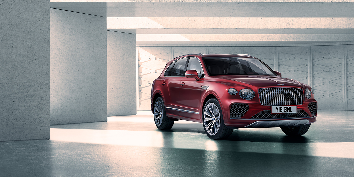 Bentley Essex (Chelmsford) Bentley Bentayga Atelier Edition SUV in Rubino Red paint front three quarter against textured concrete wall