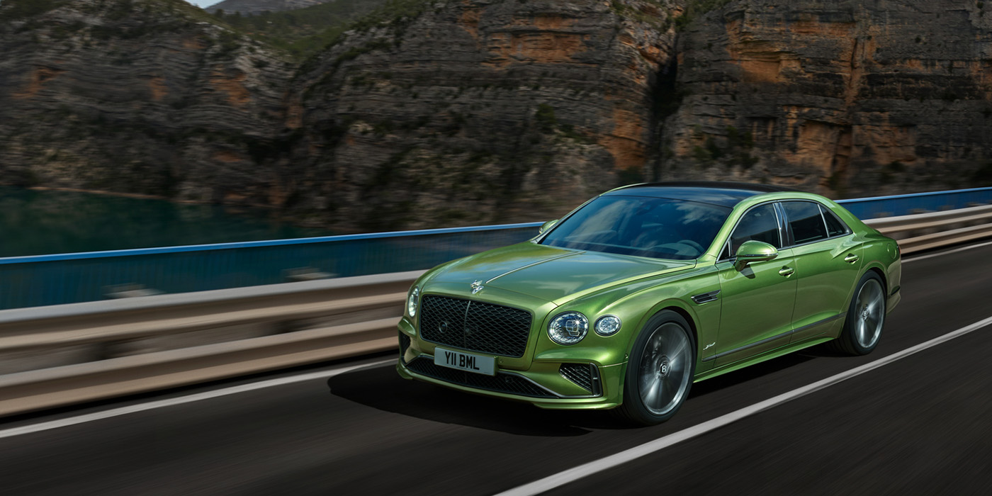Bentley Essex (Chelmsford) Bentley New Flying Spur Speed v8 hybrid sedan driving dynamically on a mountain road in Tourmaline Green paint
