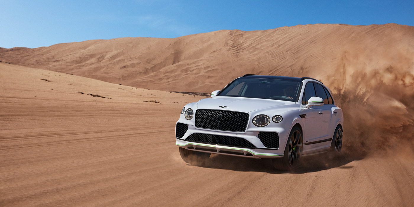 Bentley Essex (Chelmsford) Bentley Bentayga Speed SUV front three quarter in Snow Quarts Pearlescent by Mulliner white paint driving dynamically through the desert