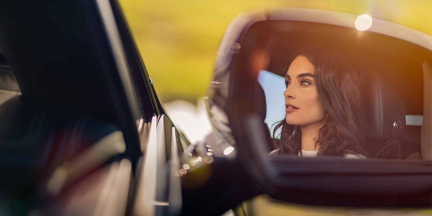 Bentley Essex (Chelmsford) profile of dark haired woman's face in mirror of Bentley car in sunlight