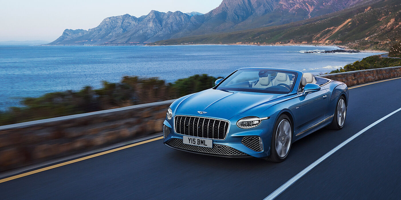 Bentley Essex (Chelmsford) New Bentley Continental GTC Azure convertible in Light Windsor blue paint with 22 inch Azure wheels and chrome grill, driving dynamically by the sea