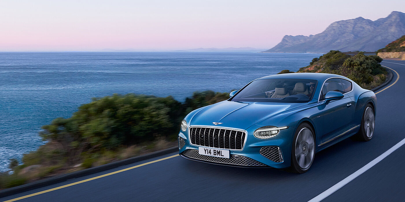 Bentley Essex (Chelmsford) New Bentley Continental GT Azure coupe in Light Windsor blue paint with 22 inch Azure wheels and chrome grill, driving dynamically by the sea