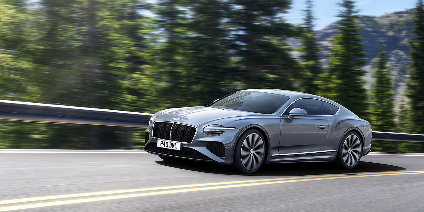 Bentley Essex (Chelmsford) New Bentley Continental GT coupe in Silverlake paint and 22 inch ten-spoke wheels, driving dynamically on a tree-lined road in the sunshine