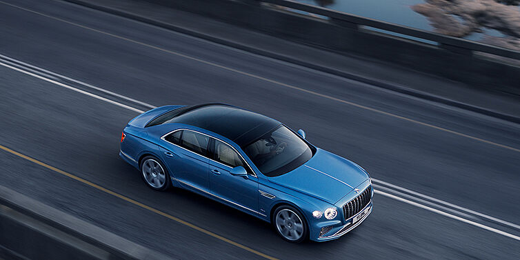 Bentley Essex (Chelmsford) New Bentley Flying Spur Azure sedan in Light windsor blue paint by Mulliner, with 22 inch Azure wheels seen from overhead driving dynamically on a country road