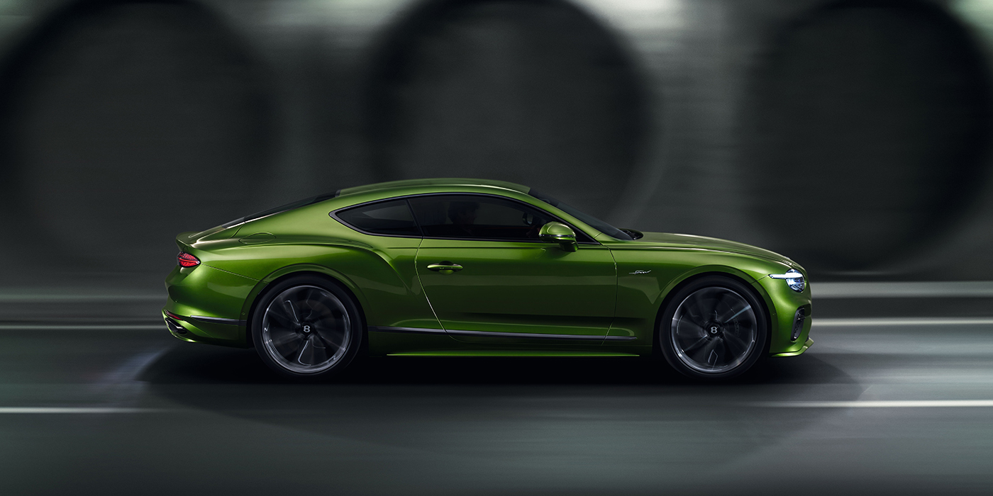 Bentley Essex (Chelmsford) Bentley Continental GT coupe in Tourmaline Green paint driving in profile on a dark road