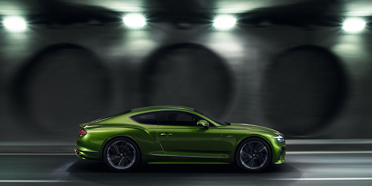 Bentley Essex (Chelmsford) Bentley Continental GT Speed coupe profile in Tourmaline Green driving dynamically past a concrete wall at night