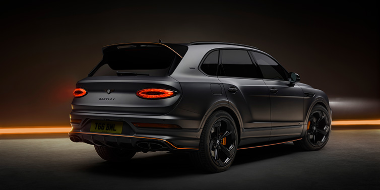 Bentley Essex (Chelmsford) Bentley Bentayga S Black Edition SUV rear three quarter in Anthracite Satin paint against a dark red and yellow background