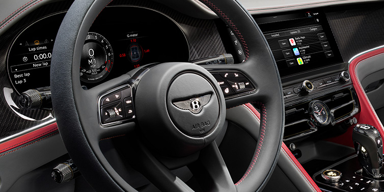 Bentley Essex (Chelmsford) Bentley Flying Spur Speed sedan front interior detail showing steering wheel and driver screens surrounded with Hotspur red and Gravity Grey hides